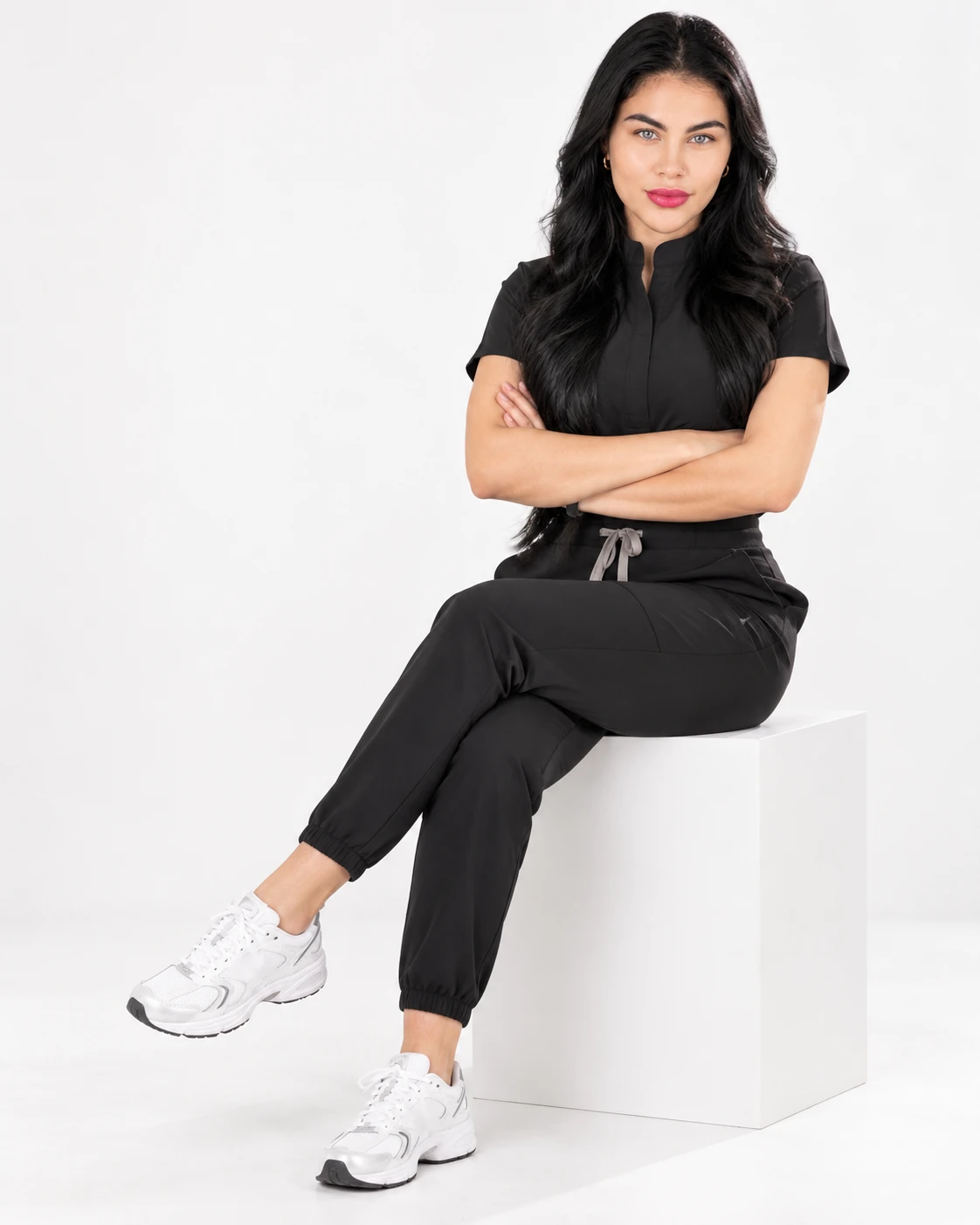 Camila, fundadora de LUNÉVIA, sentada con uniforme negro y los brazos cruzados.